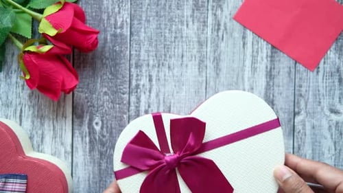 Top View of Man's Hand Putting a Gift Box on Wooden Background
