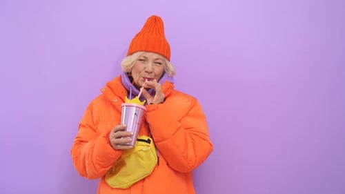 Close-up Portrait of an Attractive Older Woman Dressed in an Orange Hat and Jacket, She Poses for