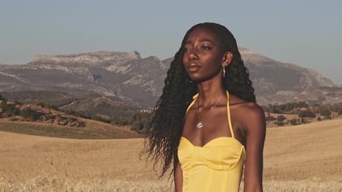 Campos abertos e mulher em pé no meio dela desfrutando da brisa quente