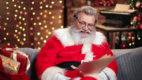 Papá Noel masculino sonriente lee la lista de deseos con expresión facial sorprendida