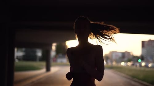 A Young Woman Runner is Training in the Summer Within a City