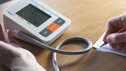 Junge Frau auf dem Sofa misst den Blutdrucktest