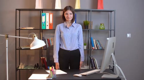 Young Woman Stretching Arms Behind Office Desk
