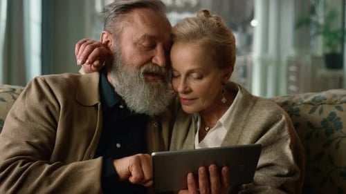 Senior Couple Using Tablet Together on Couch Indoors