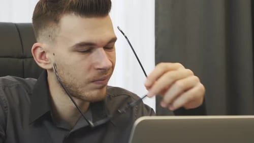 Un homme d'affaires fatigué se frotte les yeux en regardant l'écran