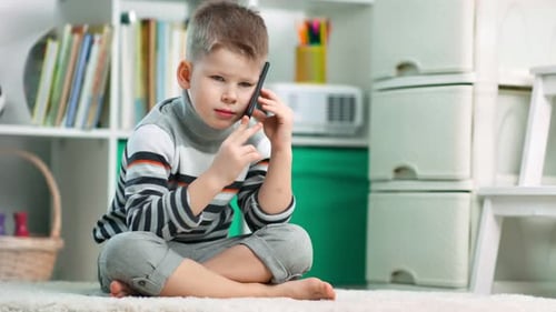 Young Boy Talking on a Mobile Phone Indoors