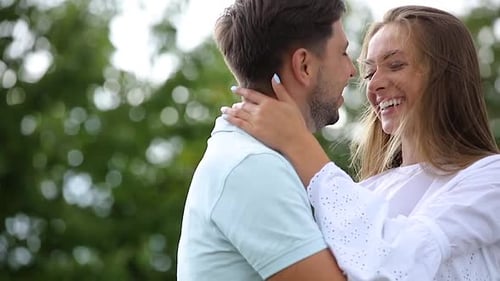 Happy Young Couple Embracing Outdoors with Joyful Smiles