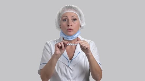 Woman in Medical Coat Presenting Pills