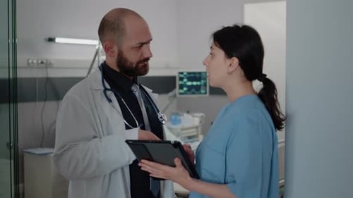 Doctor and Nurse Consulting Over Patient Data in Hospital