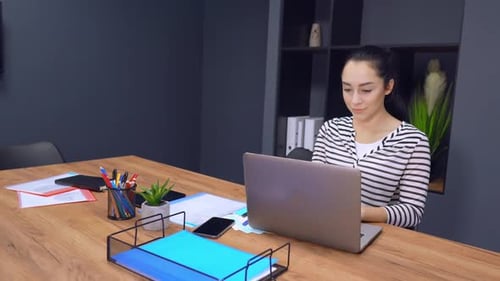 Confident Businesswoman Working on a Laptop in Her Modern Office