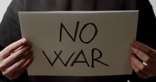 Person Holding a White Paper with a Message No War