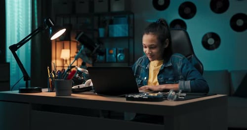 Focused Smiling Teen Uses Laptop at Home Looking at Screen Chatting Reading or Writing Email Paper