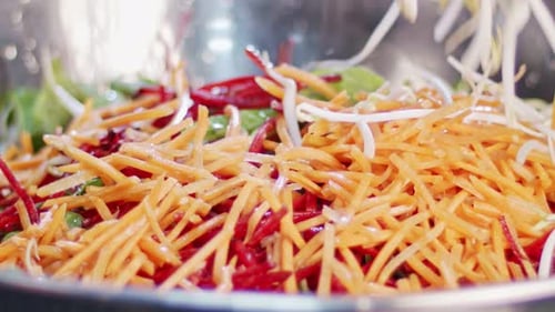 Green salad prepared in slow motion with carrots, leafs, lattuce and sprouts