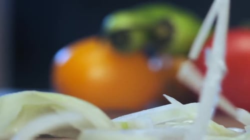 Sliced onion of white colour falls on brown wooden board