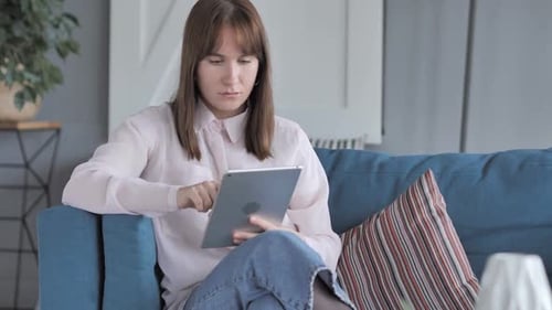 Young Woman Using Tablet on Teal Couch