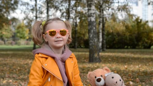 Cute Child Waving in an Autumn Park