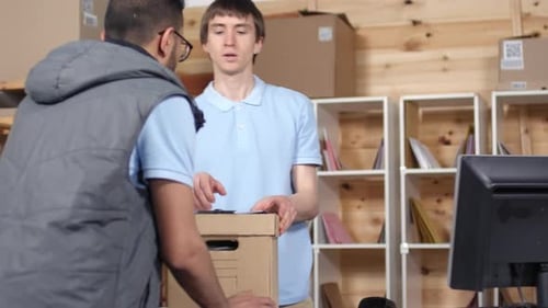 Male Courier Handing in Parcel at Post Depot