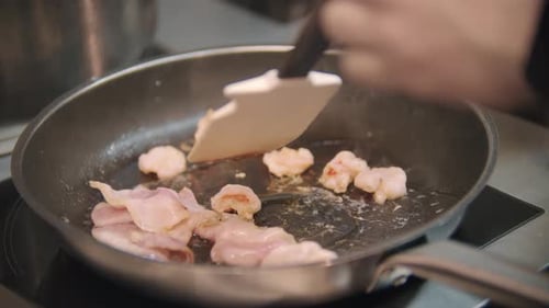Restaurant Cooking Chef Roasts Bacon Pieces in a Frying Pan