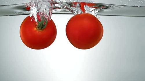 Slo-motion beefsteak tomato falling into water