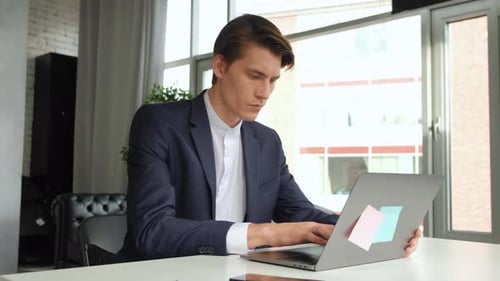 Kreativer Unternehmer, der an seinem Schreibtisch sitzt, arbeitet im stilvollen Büro am Desktop-Computer