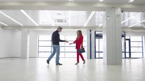Businessman Shakes Hands with Realtor Woman After Concluding an Office Lease Deal Front View