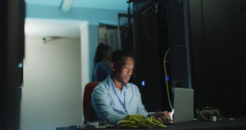 Young Adult Works on Laptop in Server Room
