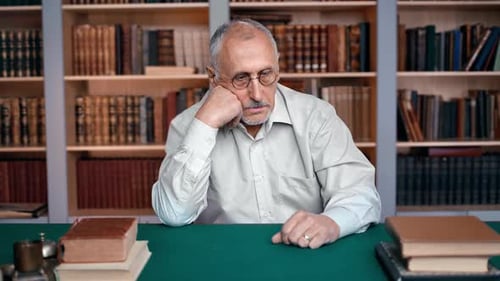 Senior Man Sitting at Desk with Books