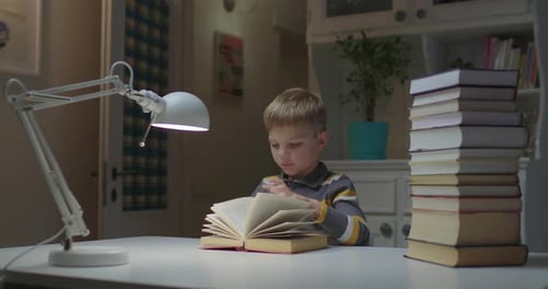 Boy Reading Book at Desk with Lamp