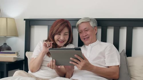 Senior Couple Enjoying Tablet in Bright Bedroom