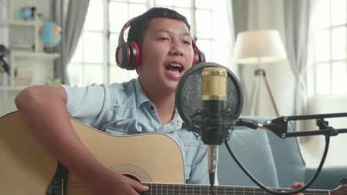 Chico vlogger con guitarra hablando con la cámara mientras transmite. El niño está transmitiendo