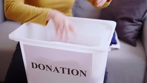 Detail der Frau, die Kleidung für Spenden auswählt. Konzept für Kleidungsspenden.