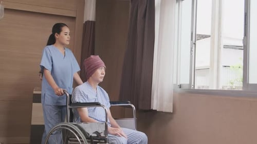 Woman in wheelchair with nurse in hospital room