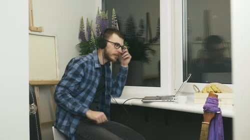 Man takes off headphones after work on laptop computer from home