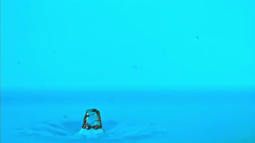 Super Slow Motion Water Falls on the Table on a Blue Background