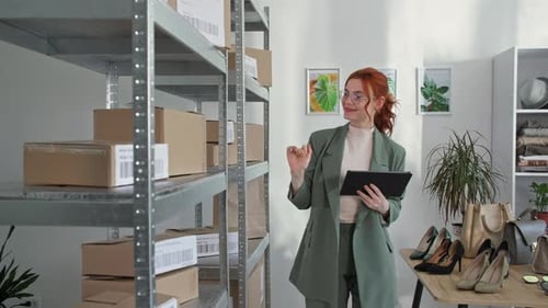 Loja de roupas on-line: mulheres sorridentes segurando um tablet na mão, verificando pedidos de clientes para enviar