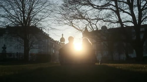 Couple Relaxing In Park On Bench As Sunsets