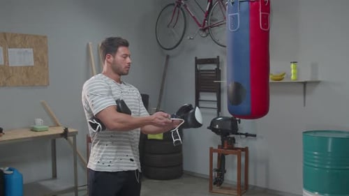 Man Puts on Boxing Gloves at the Gym