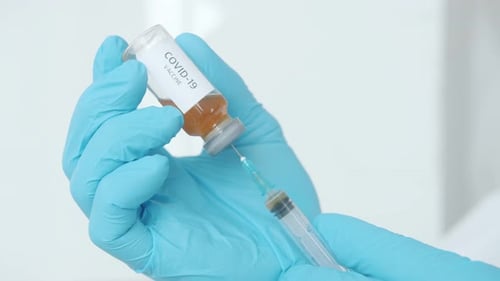 Closeup of Male Hand in Medical Glove Using Covid19 Vaccine Bottle and Syringe in Hospital