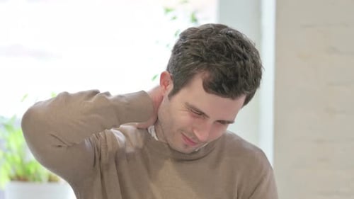 Young Adult Rubs Sore Neck Indoors