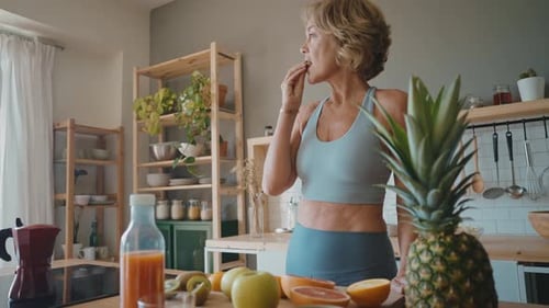 Woman Enjoys Fruit in her Sunny Kitchen