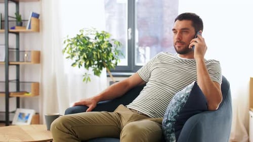 Man Talking on Phone in Armchair at Home