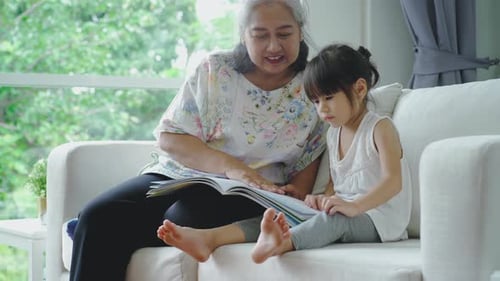 Grandmother Reading to Granddaughter on the Sofa