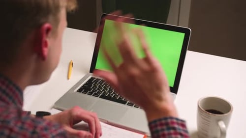 Vista trasera Hombre de cerca agitando la mano en la cámara portátil con pantalla verde Chromakey Hombre tiene videollamada