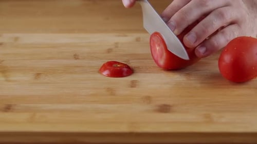 Slicing Fresh Red Tomato On The Chopping Board In The Kitchen - close up