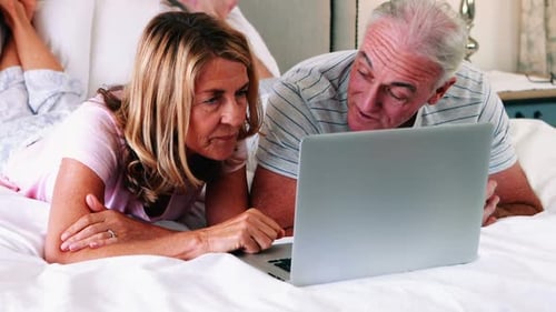Couple Using Laptop Computer Together on Bed