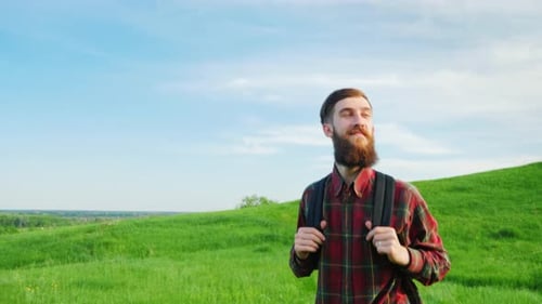 A Young Bearded Hipster Man with a Backpack Behind Him