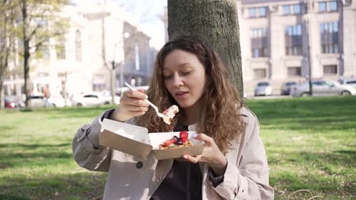 Woman Enjoys Delicious Cake with Fresh Fruits in City Park