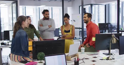 Groupe diversifié de collègues de travail regardant un écran d'ordinateur et parlant