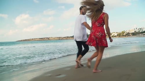 Lovely Couple Run Along the Beach Holding Hands