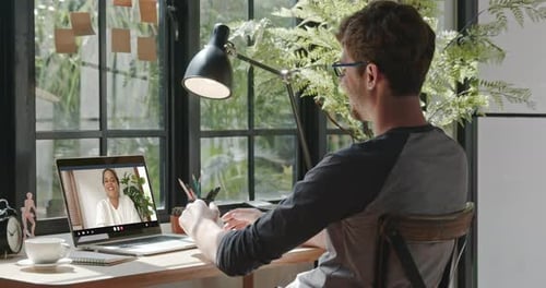 Man Attends Virtual Meeting at Desk at Home